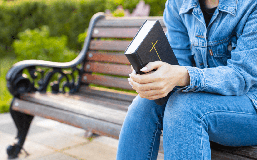 Woman sitting on bench holding Bible